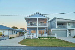 A two-story residential building with a balcony on the upper floor, a garage, and a well-maintained lawn. - Blu Bay View—Stroll Down to the Bay at Golden Hour (Geographe)