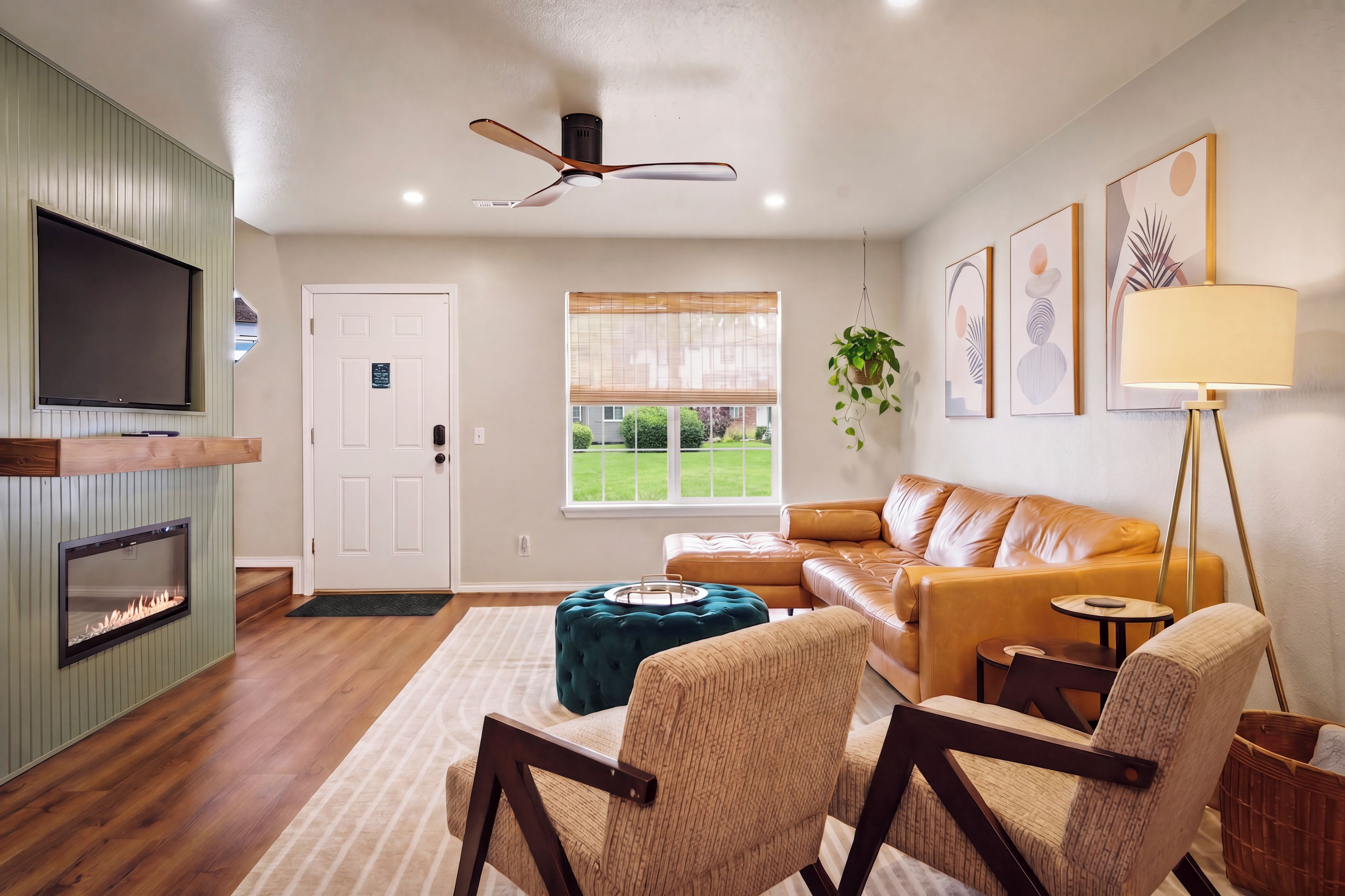 A living room with a fireplace, a ceiling fan, a sofa, a coffee table, and a TV mounted on the wall.