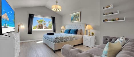 A modern bedroom with a bed, bedside tables, a TV, a sofa, and a window with curtains.