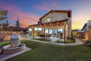 A house with a covered patio, outdoor seating, and a stone fire pit. - Travelers Dream|Monthly Stays|Strip in the Horizon (Las Vegas)
