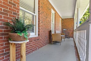 A covered porch with a brick wall, a potted plant, wicker chairs, and a table. - Peaceful Luxury Retreat Short Drive to Columbia (Lexington)