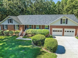 A two-story house with a front garage, a covered porch, and a well-maintained lawn. - Peaceful Luxury Retreat Short Drive to Columbia (Lexington)