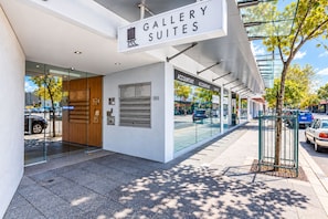 Ein modernes Gebäude mit einem Schild für 'Gallery Suites' und einem Verzeichnis, das Dienstleistungen wie Steuerberater und Rechtsanwalt auflistet.