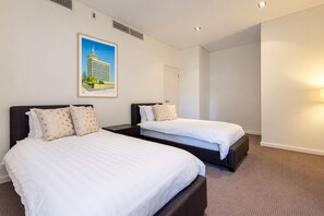 Ein Hotelzimmer mit zwei Betten, einem gerahmten Bild an der Wand und einer Tür zu einem weiteren Raum.