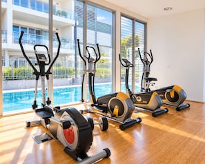 Ein Fitnessstudio mit Trainingsgeräten, einem Pool und großen Fenstern.