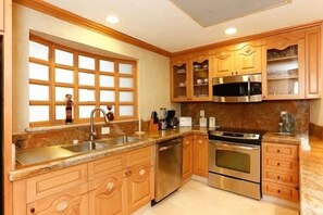 A kitchen with wooden cabinets, stainless steel appliances, and a granite countertop. - Estancia on Medano Beach! Ideal location, close to beach-end! (Cabo San Lucas)