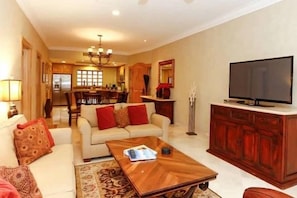 A living room with a sofa, coffee table, TV, and a dining area in the background. - Estancia on Medano Beach! Ideal location, close to beach-end! (Cabo San Lucas)