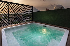 A hot tub with a view of a cityscape through a geometric metal fence.