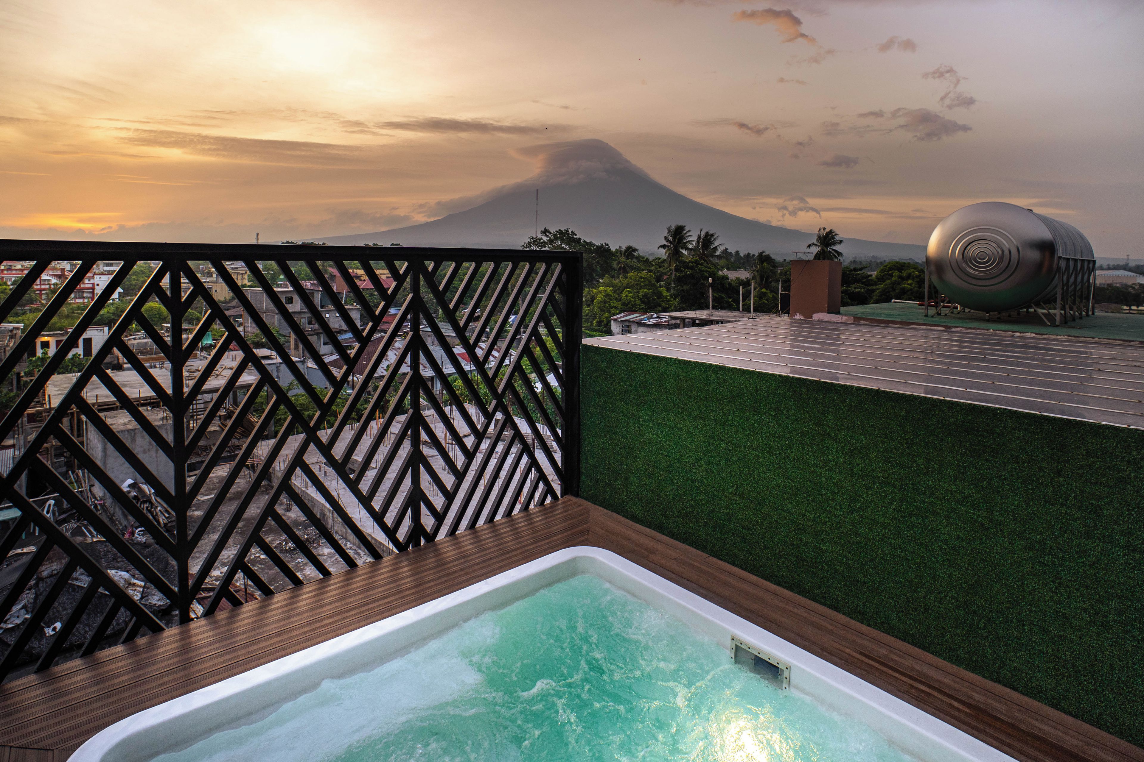 A rooftop pool with a view of a volcano and a large cylindrical structure.