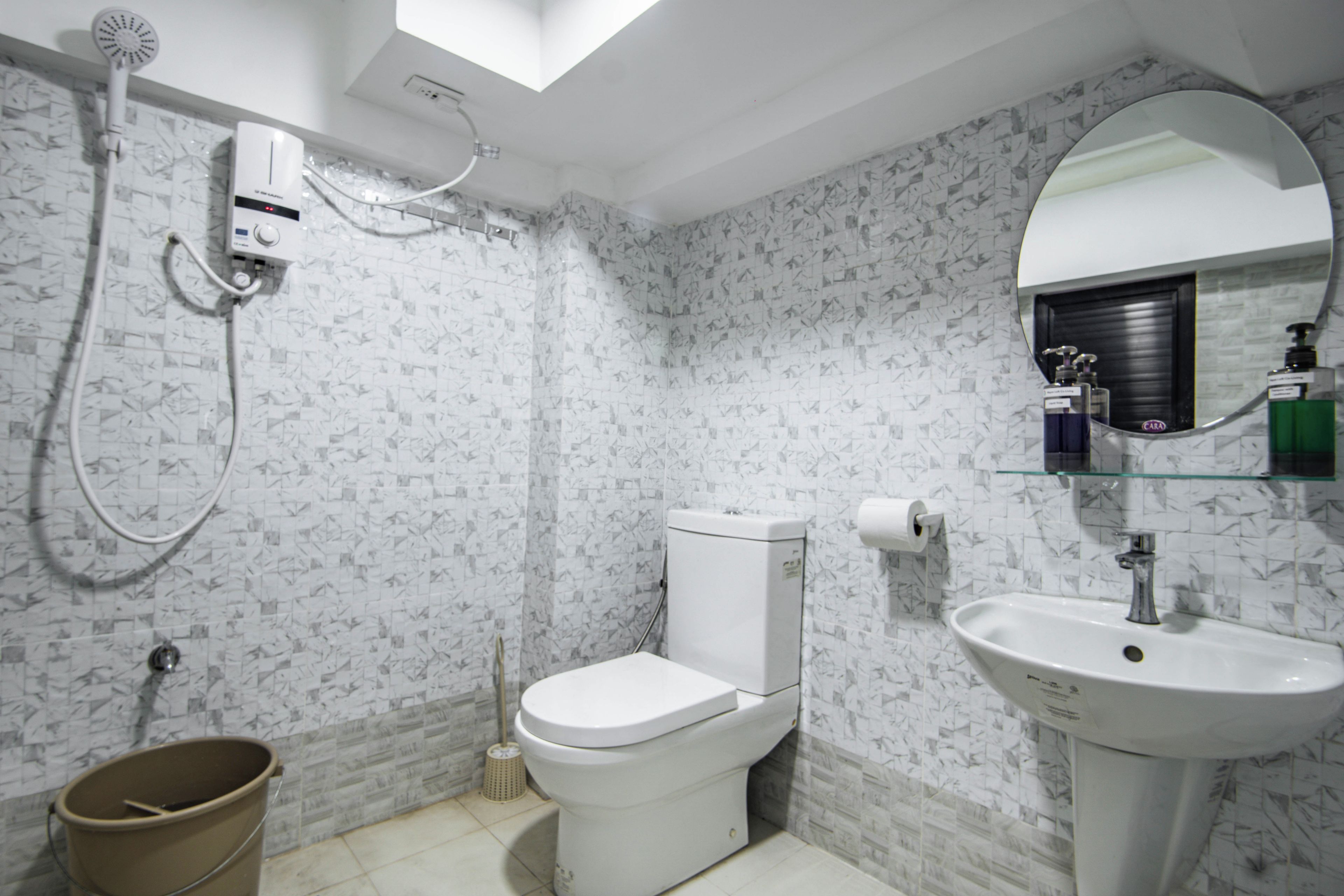A bathroom with a toilet, sink, shower, and a mirror.