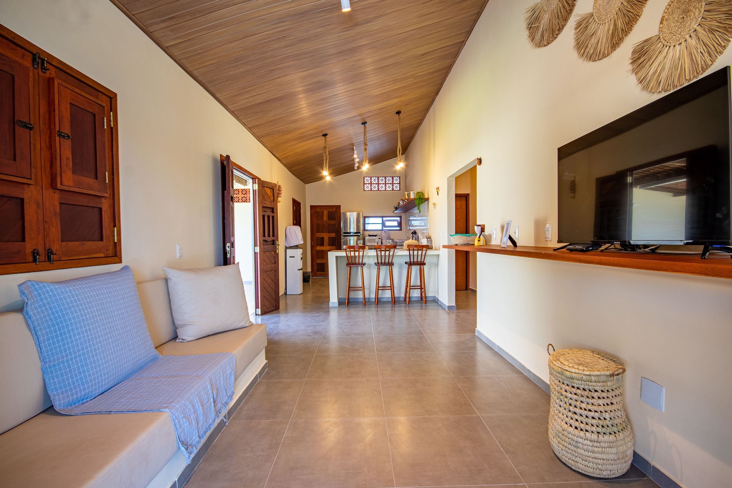 A modern kitchen with a central island, wooden cabinets, and a large TV.