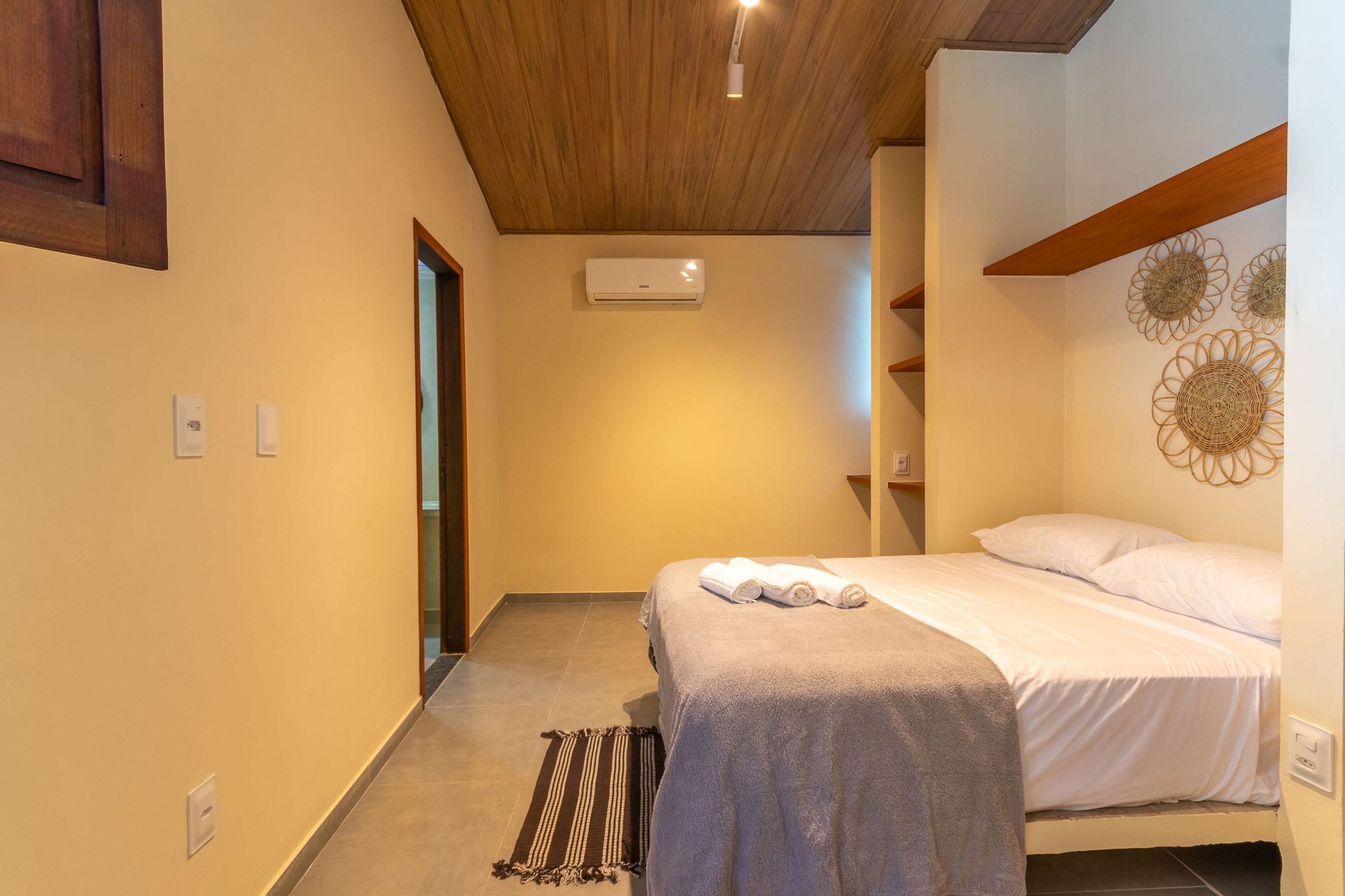 Una camera da letto con un letto, un condizionatore d'aria a parete e una porta che dà su un'altra stanza.
