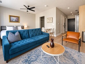 Ein modernes Wohnzimmer mit einem blauen Sofa, einem Couchtisch und einem braunen Sessel.