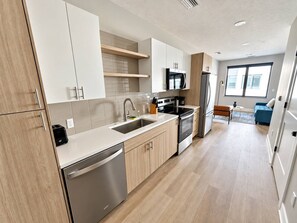 Une cuisine moderne équipée d’un lave-vaisselle, d’une cuisinière, d’un four à micro-ondes et d’un évier. Un coin repas avec une table et des chaises est également à disposition.