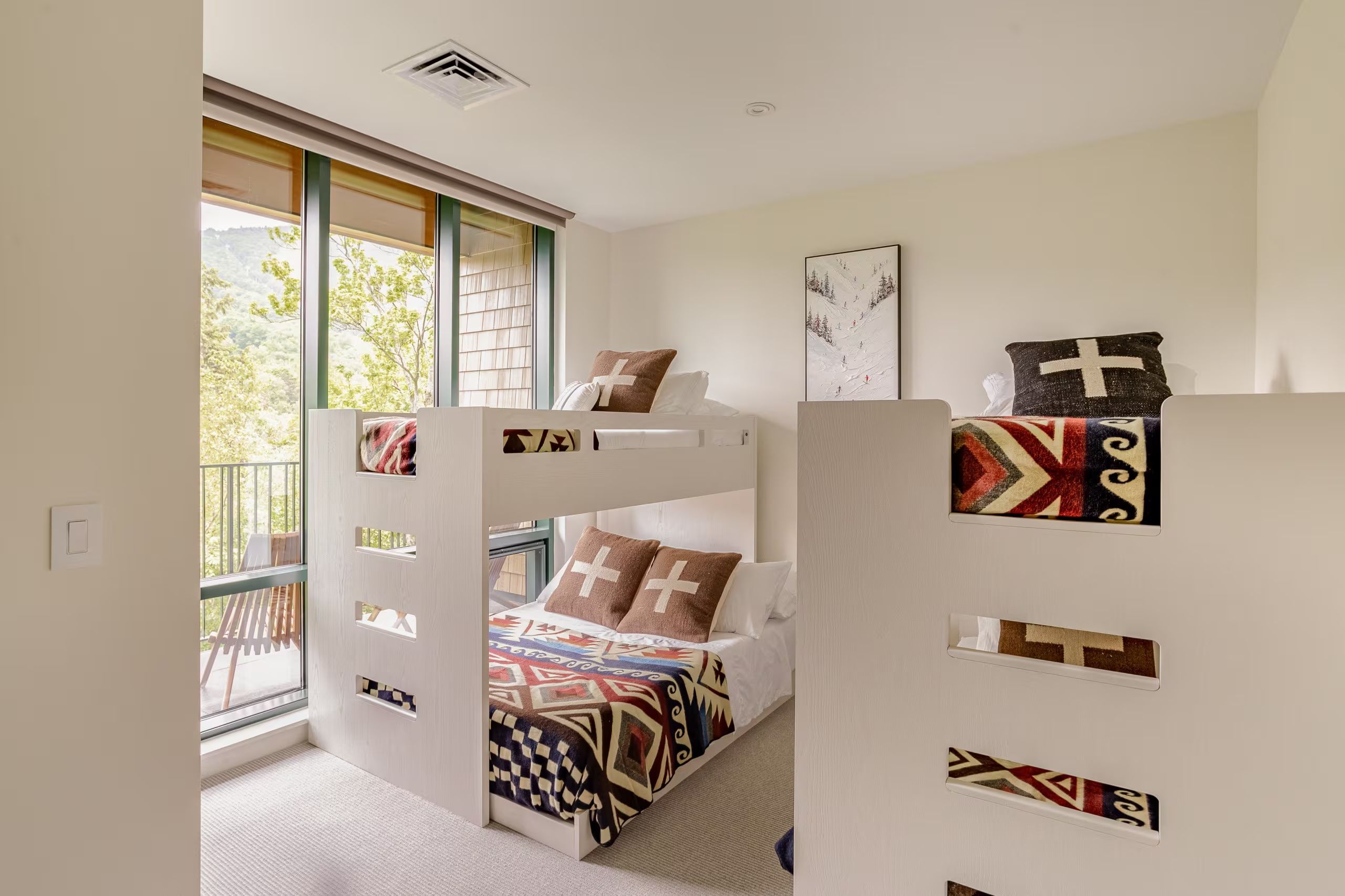 Un dormitorio con literas, una ventana con vistas y una puerta con detalles decorativos.