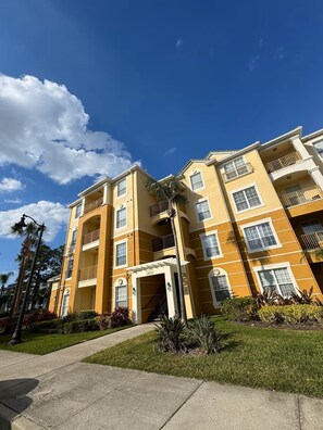 A multi-story residential building with a central entrance, balconies, and a well-maintained lawn. - Spacious 3BR condo in Orlando, perfect for families, sleeps 8 comfortably. (Orlando)