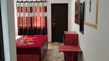 Una habitación con cama, escritorio, espejo y ventilador de techo.