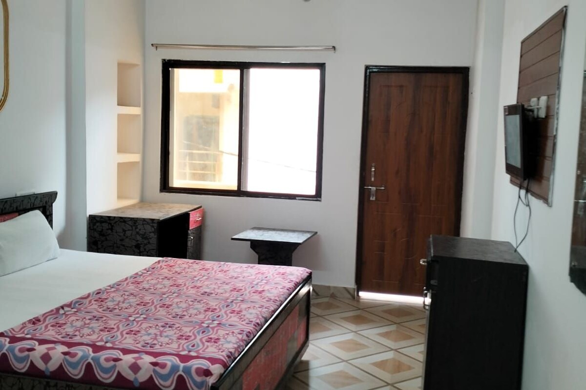 Quarto com cama, janela, porta e televisão.