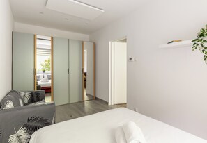 Ein Schlafzimmer mit Bett, Kleiderschrank, Nachttisch und einer Pflanze.