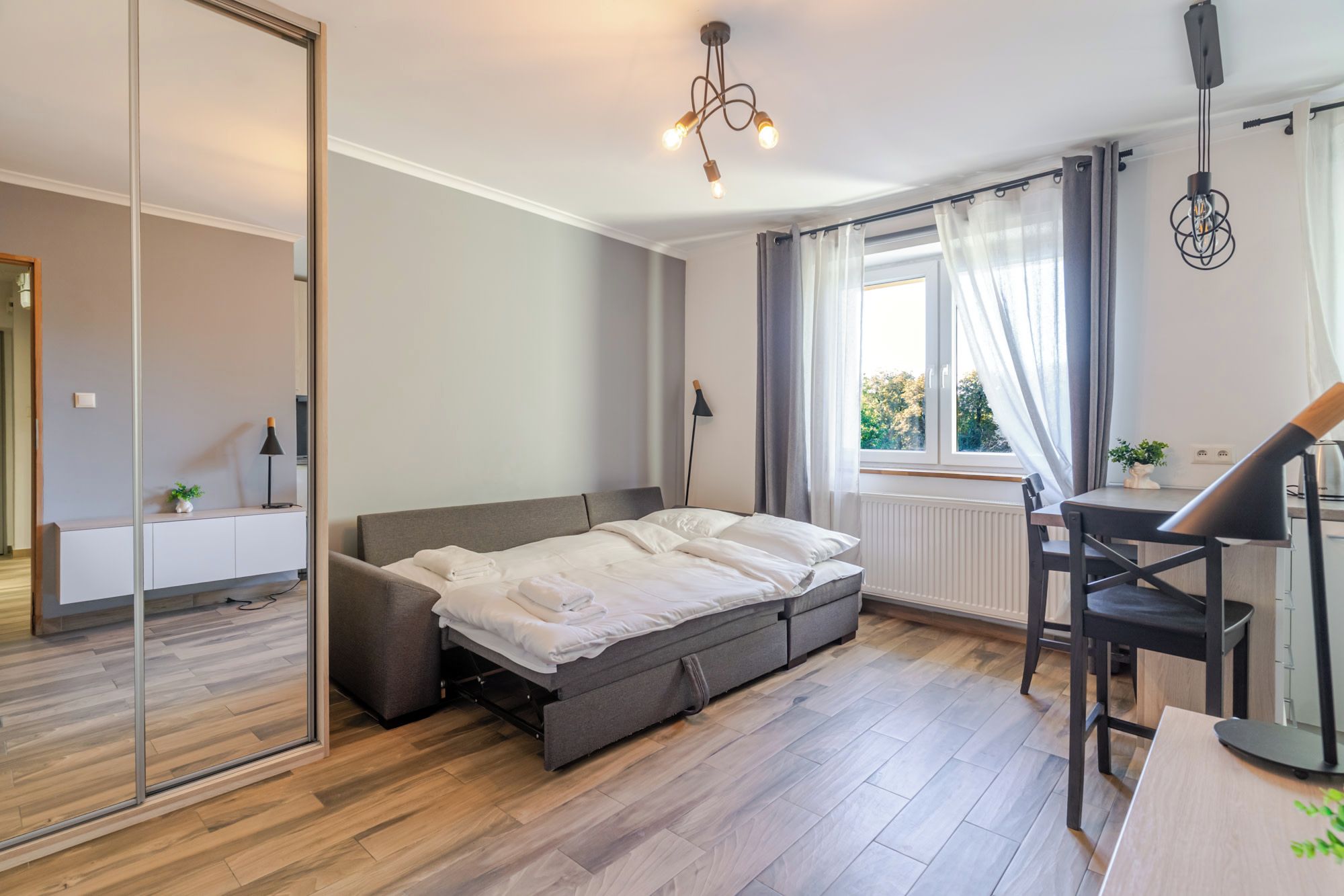 Un dormitorio moderno con cama, mesita de noche y un espacio de escritorio.