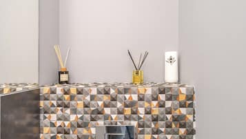 Un baño con salpicadero de azulejos, un espejo y dos recipientes decorativos en un estante.