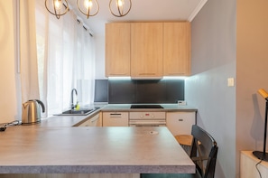 Una cocina moderna con armarios de madera, horno empotrado y hervidor de acero inoxidable.