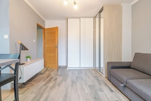 Una sala de estar moderna con un sofá gris, una puerta de madera y un escritorio con una lámpara.