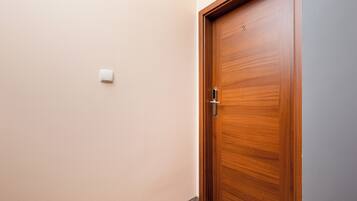 Una puerta de madera con un picaporte y un pequeño interruptor de luz en la pared.