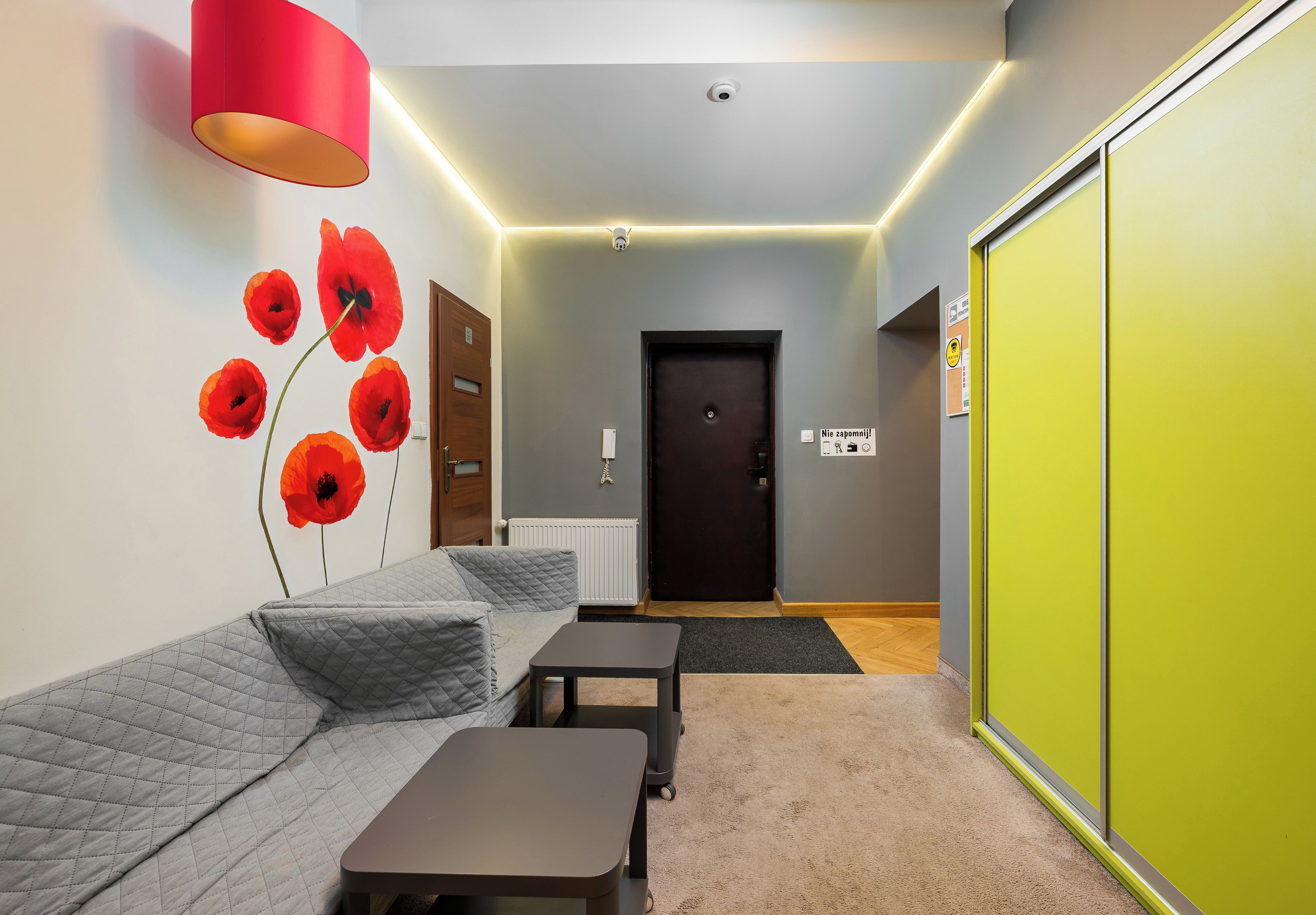 Habitación de hotel con sofá, una mesita, un radiador y una puerta con un cartel.