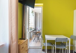 A small room with a white table, two chairs, a wooden cabinet, and a television on the wall. - Hostel Moderna Rest Room 6 (Katowice)