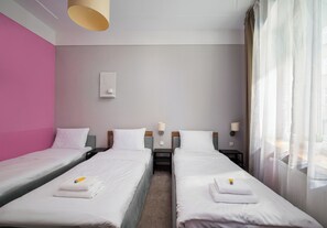 A hotel room with two single beds, a nightstand with a lamp, and a window with sheer curtains. - Hostel Moderna Rest Room 3 (Katowice)