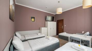 Una habitación de hotel con dos camas, un escritorio, un televisor y un armario.