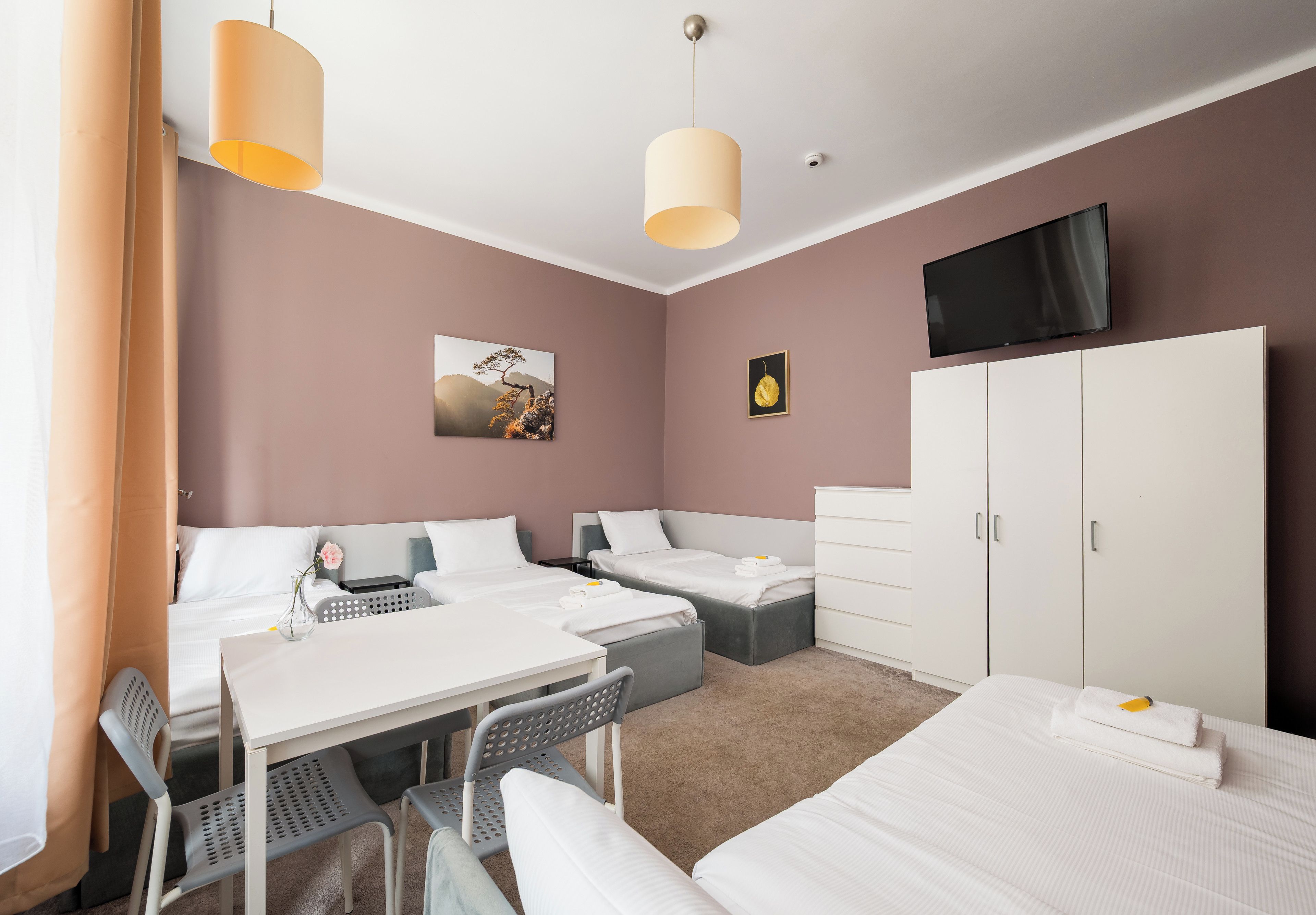 Ett hotellrum med två sängar, ett skrivbord, en stol, en TV och en garderob.