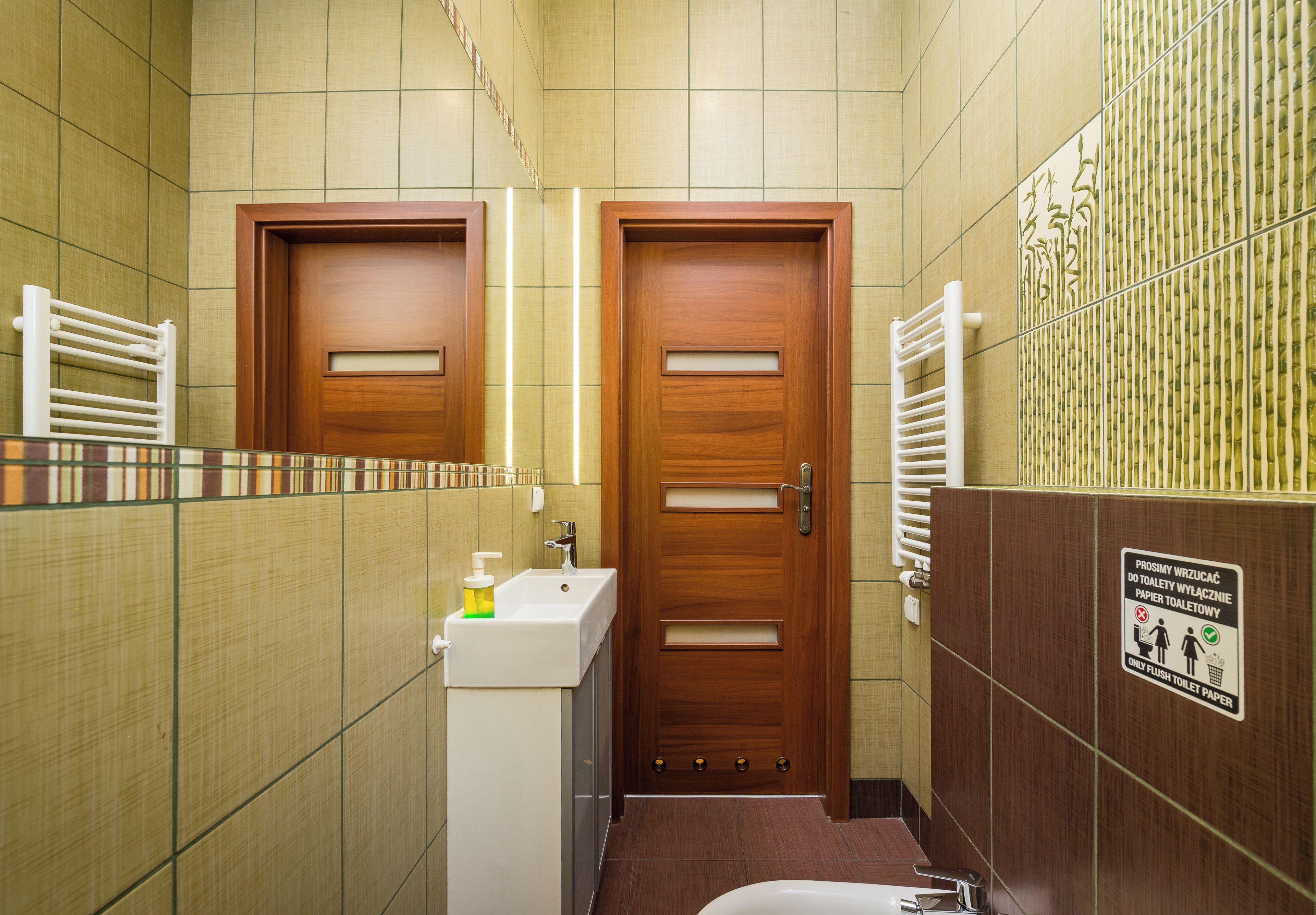Une salle de bain avec une porte en bois, un lavabo avec un distributeur de savon et des toilettes.