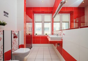 Ein modernes Badezimmer mit roten und weißen Fliesen, einer Toilette, einem Waschbecken und einem Fenster.