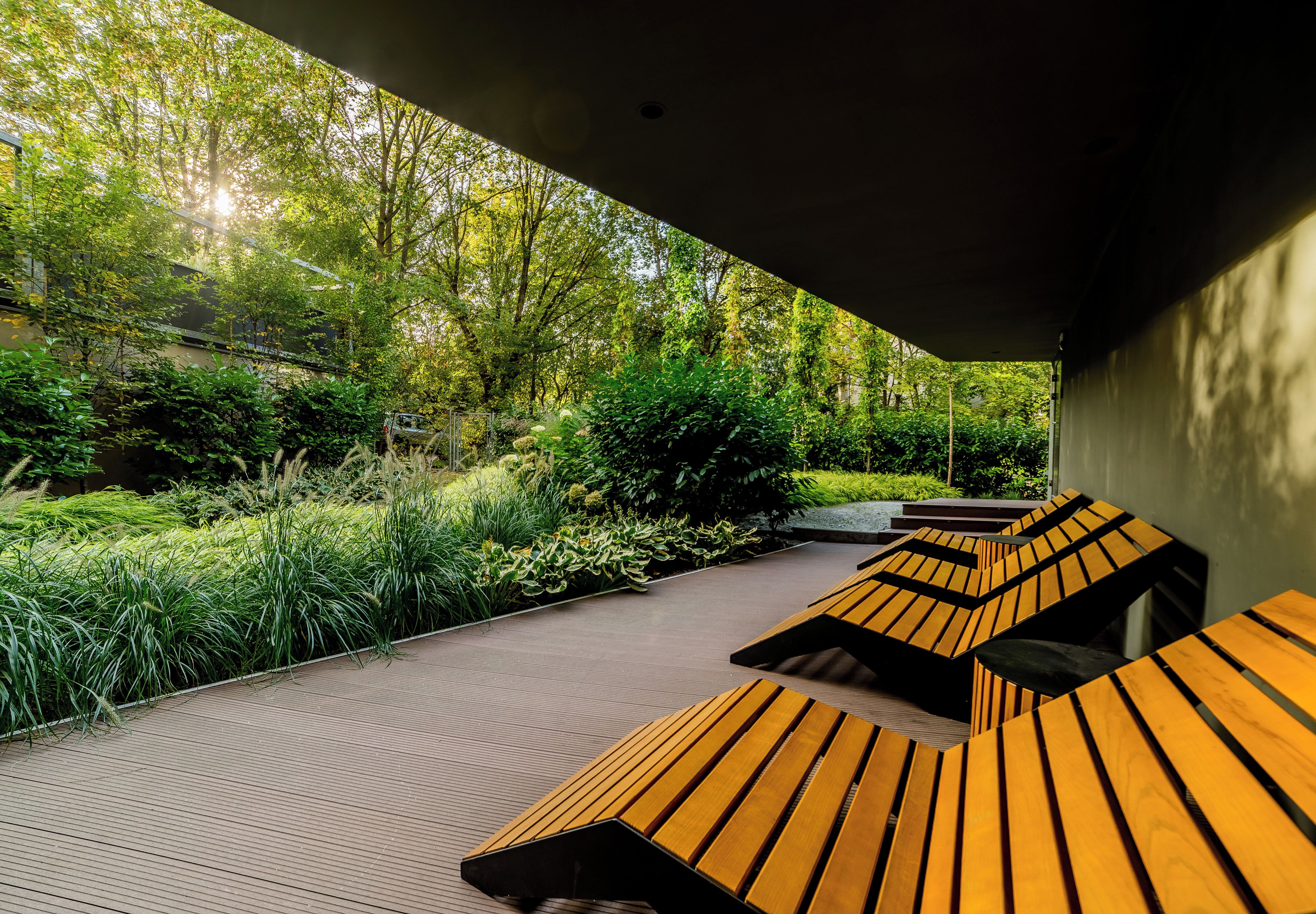 Un espace extérieur abrité, doté de bancs en bois et d’un chemin bordé de verdure.
