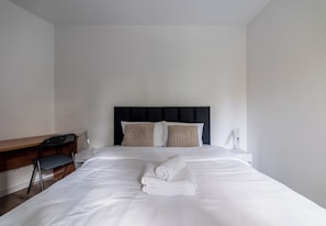 Ein Hotelzimmer mit Bett, Schreibtisch, Stuhl und Nachttisch.