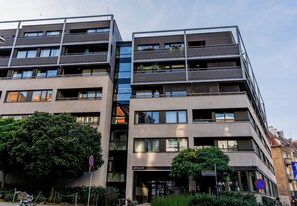 Ein mehrstöckiges Gebäude mit Balkonen, einem sichtbaren Eingang und einem Schild mit der Adresse.