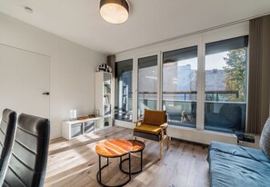 Un salon moderne comprenant un canapé, deux fauteuils, une petite table et une bibliothèque.