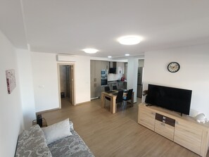 A modern living room with a sofa, a TV, and a dining area with a table and chairs. - Beachfront · Ocean views · Pet-friendly upon request (Los Arenales del Sol)