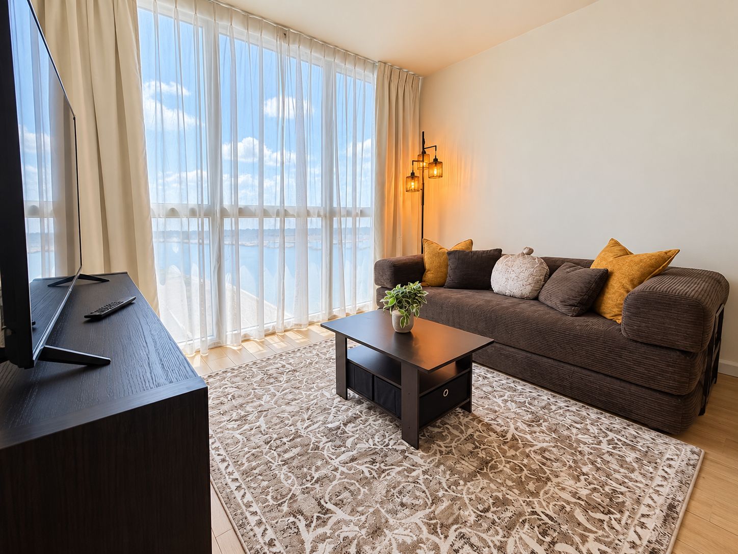 Una sala de estar moderna con un ventanal grande, un sofá, una mesa de centro y un televisor.