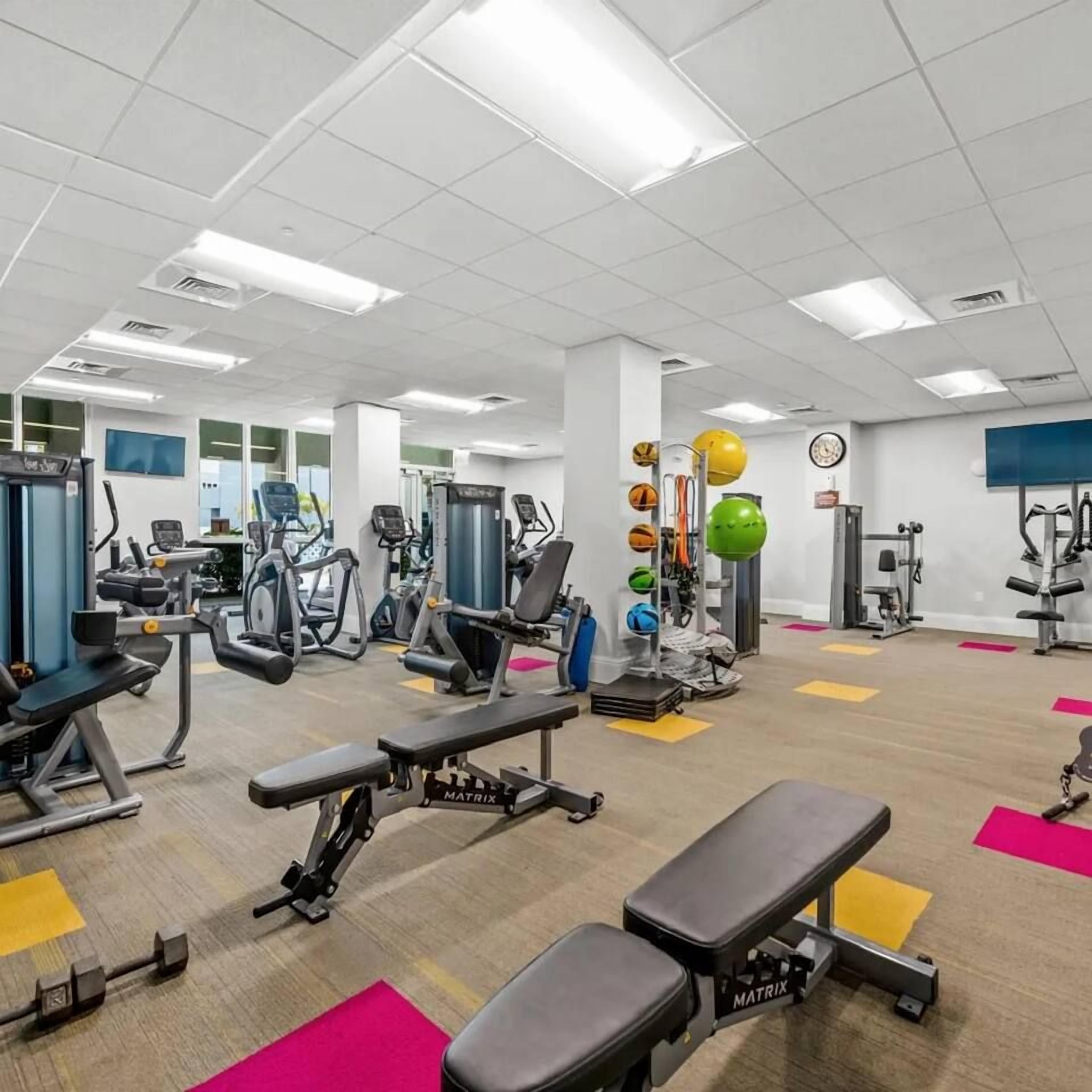 A gym with various exercise equipment, including treadmills, weight machines, and free weights.