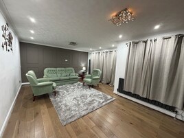 Una sala de estar con un sofá gris, un tapete estampado y un radiador.