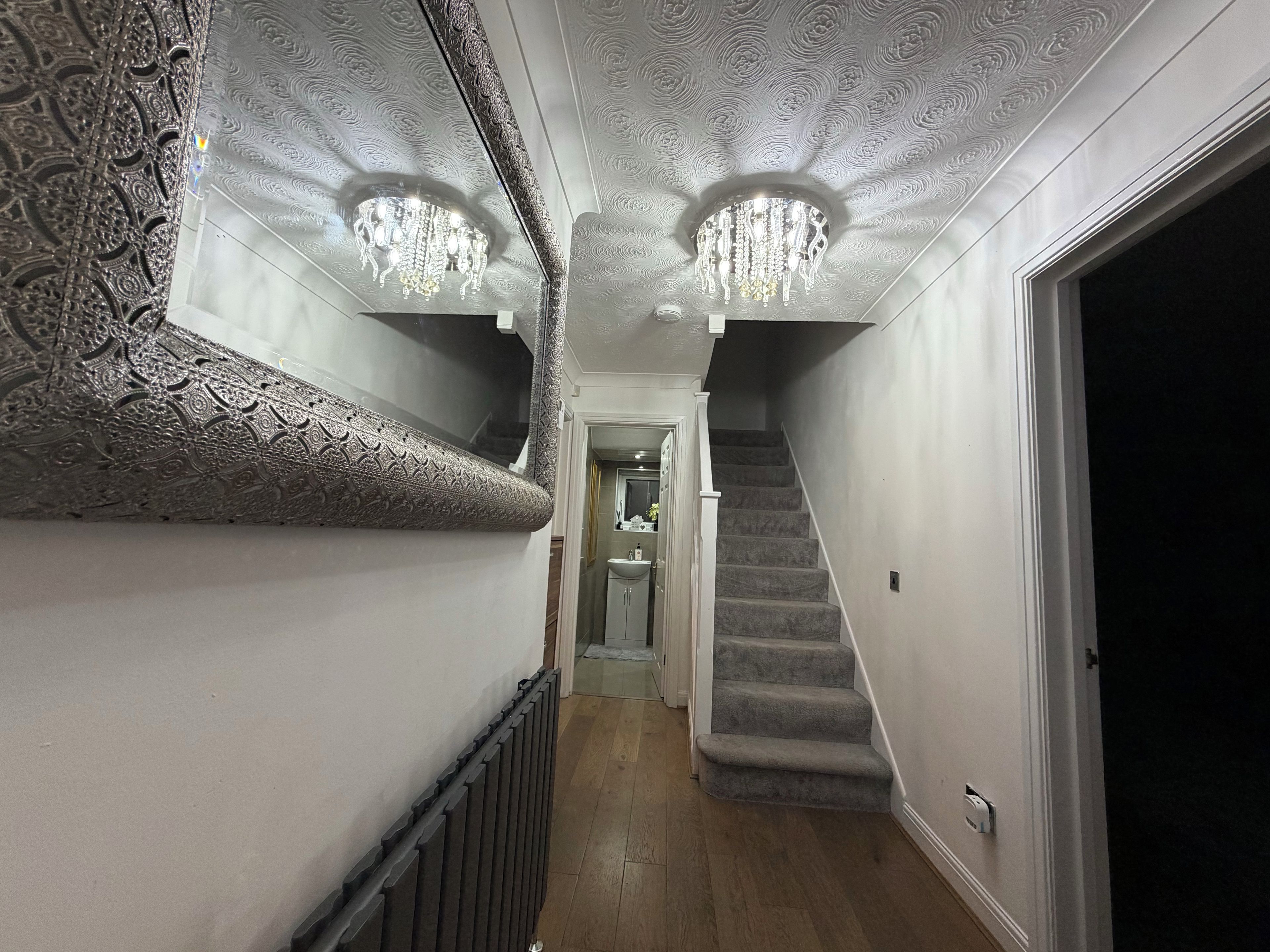 A hallway with ornate wall moldings, a staircase, and a chandelier.