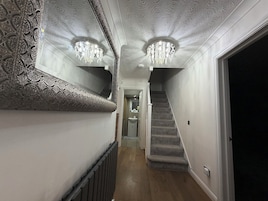 A hallway with ornate wall moldings, a staircase, and a chandelier.