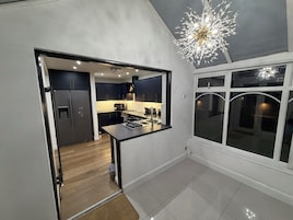 A modern kitchen with dark cabinets, a stainless steel refrigerator, and a central island.