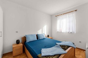 Ein Schlafzimmer mit einem Bett, Nachttischen, einem Fenster mit Vorhängen und Holzboden.