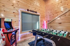 Ein Zimmer mit Holzwänden, einem Kicker und einer Spieluhr.