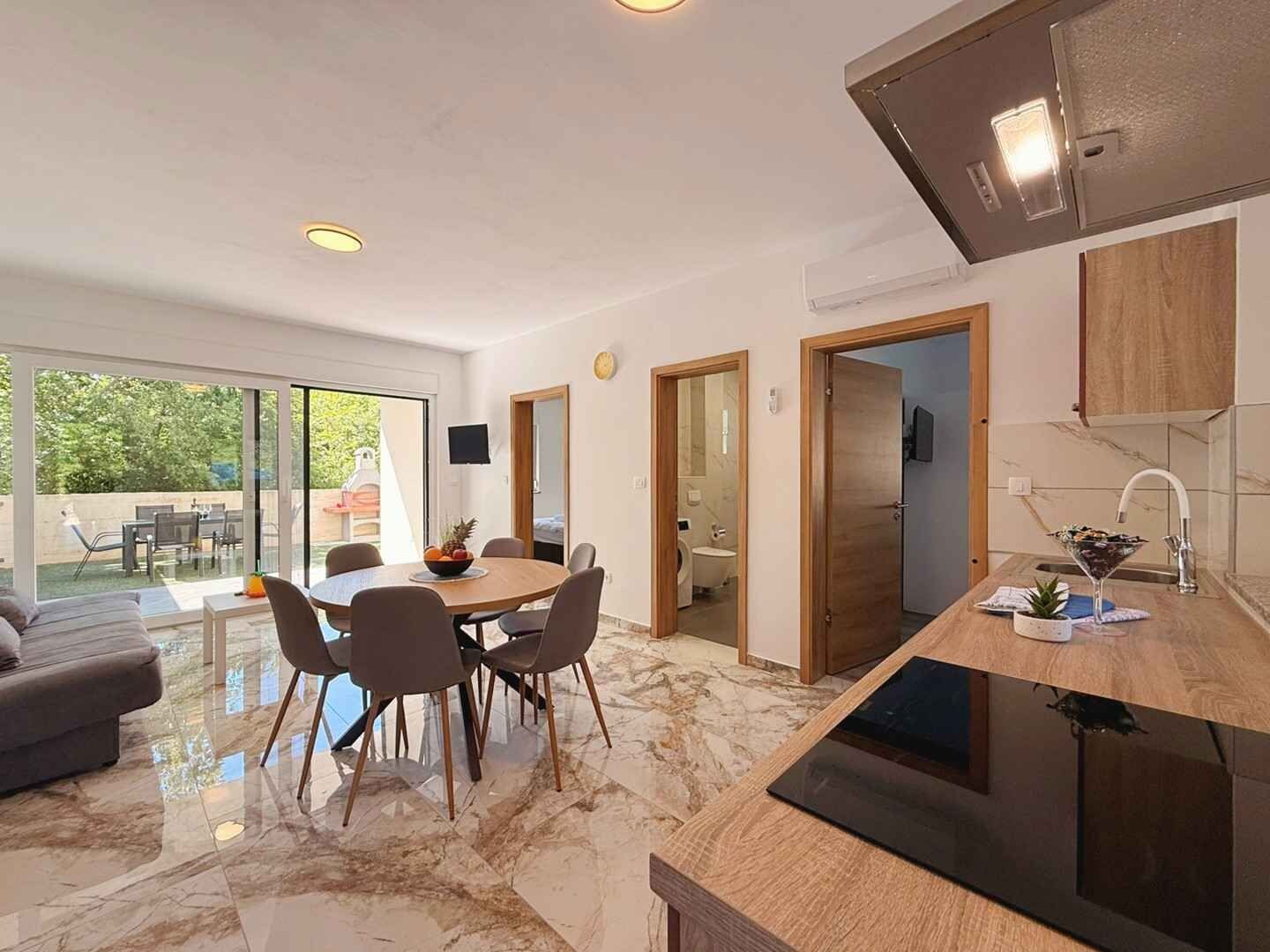 A modern kitchen with a dining area, a large window, and a view of the outdoors.