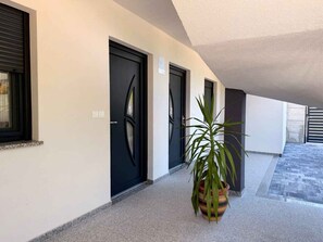A hallway with three black doors, a potted plant, and a tiled floor. - Holiday apartment with shared use of pool (Polje/Krk)